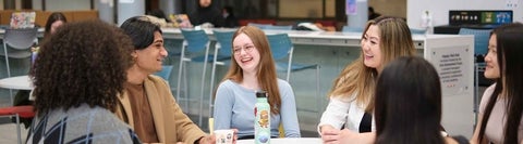 Six students sitting around a table chatting together