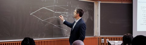 Professor writing on a chalkboard in front of students