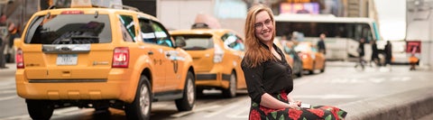 Student smiling in front of taxi cabs