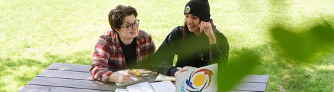 students sitting at a bench in park