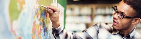 Person using chalk to point at the map on the whiteboard.