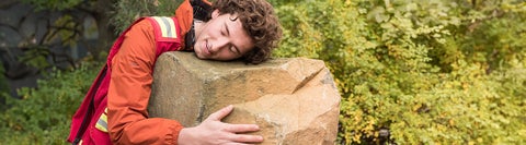 Student hugging a large rock