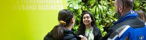 Students in the Environment building. A plant filled wall is behind them.