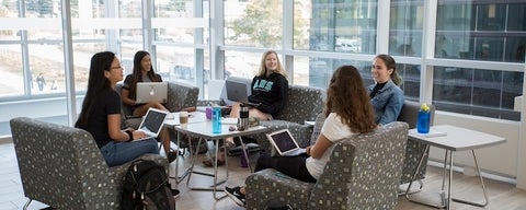 A group of students sitting on couches with their laptops open