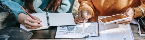 Two students writing in notebooks