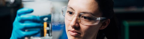 girl in lab googles looking at experiment