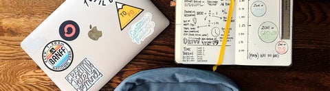 A laptop, notebook, and backpack laid out on a table. 