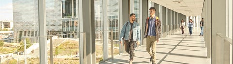 Students walking across indoor bridge