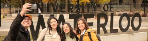Students taking a group selfie in front of the University of Waterloo sign