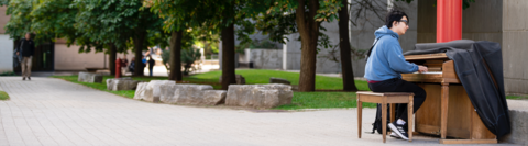 Student playing the piano outside on campus. 