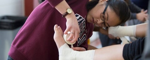 A student wrapping a foot with medical tape