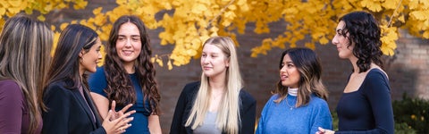 Group of students in business attire standing outside talking