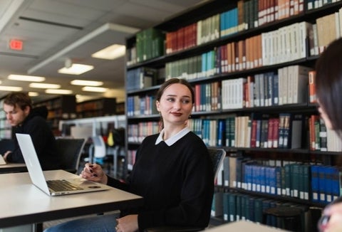 Student sitting with laptop in a library.