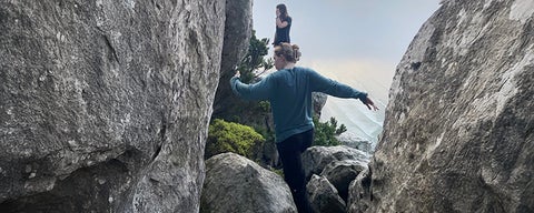 Liz hiking, jumping between two rocks.