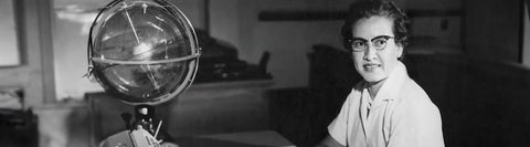 black and white photo of women sitting by a globe 