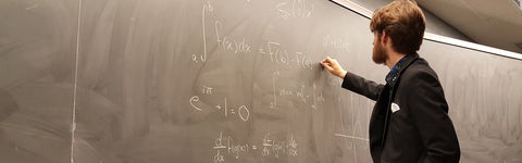 A Math/Teaching student writes an equation on a chalkboard