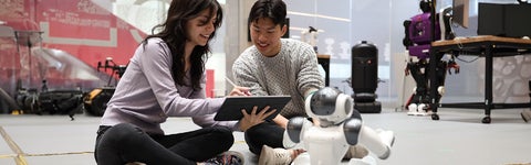 two students looking at a robot