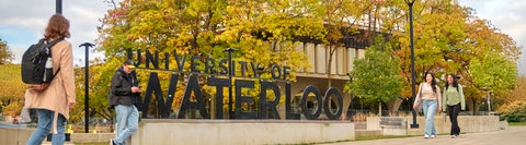 University of Waterloo sign on campus with students walking 