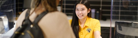 A student behind a counter greeting another student