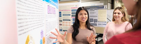 Public Health student stands in front of poster board explaining her work