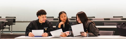 Three University of Waterloo students in a classroom compare notes