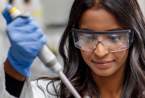 student in gloves performing an experiment. 