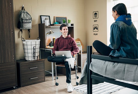 two students sitting in a dorm room talking 