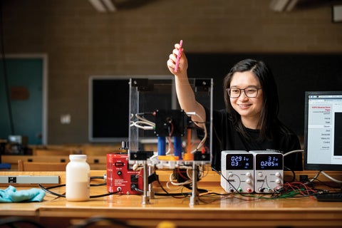 Student working at wooden table with equipment on top