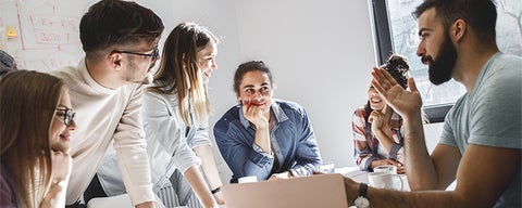 Group of people collaborating around a table, discussing work.