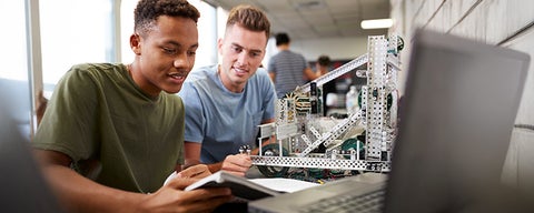 Two people working on a project beside a laptop.
