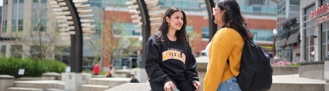 Two students standing in Uptown Waterloo conversing.