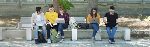 Students with laptops sitting on a bench