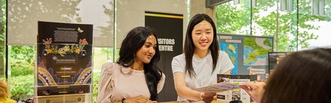 Two students check in at the front desk in the University of Waterloo Visitors Centre