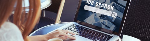 Student typing on laptop. Text on the laptop screen says "job search"