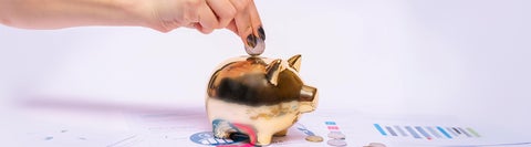 Hand putting coins into a piggy bank
