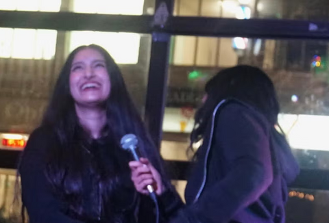 Iman and her friend laughing together while doing karaoke. 