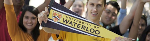 student holding Waterloo pennant in front of happy crowd with raised hands