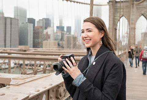 Student standing on a bridge with a camera in her hands