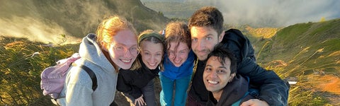 Environment students huddle together and smile on a mountain top