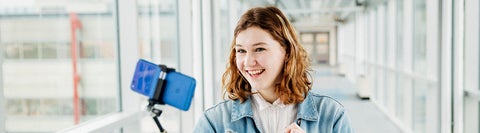 student standing in glass hallway taking a selfie