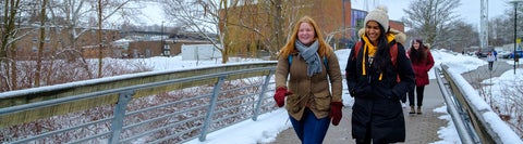 Students in winter coats walk across a small bridge at the University of Waterloo