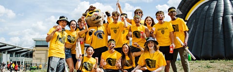 Students in gold shirts pose for the camera