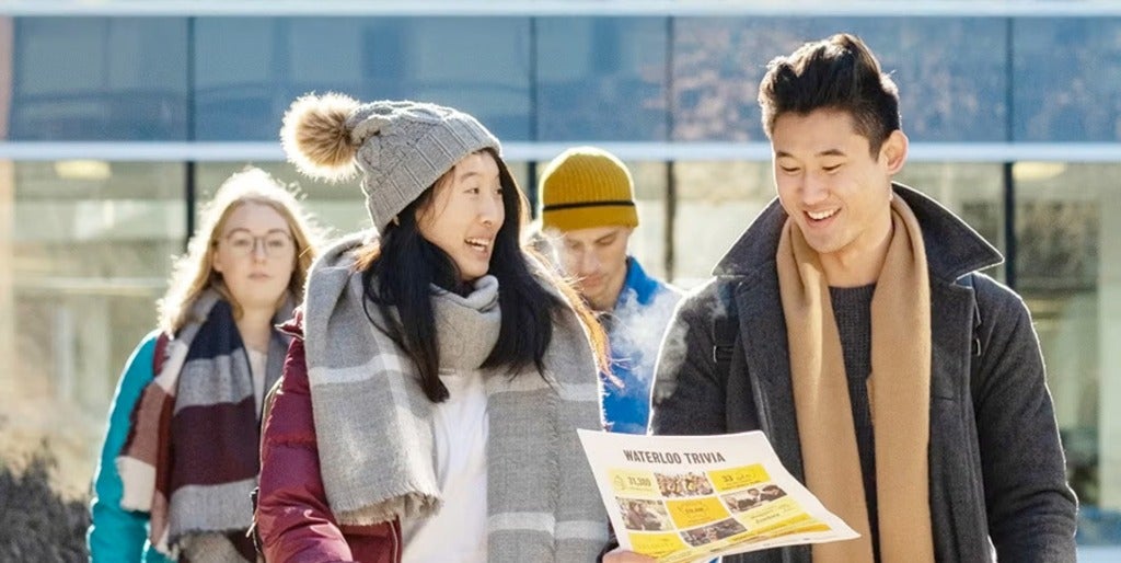 Students walk holding an open house flyer