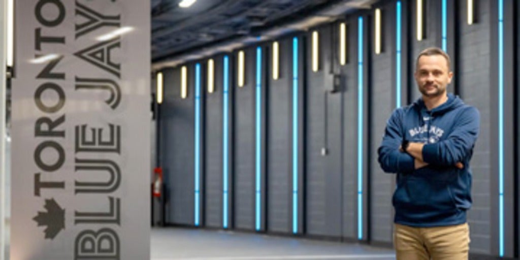 Waterloo alum standing with Blue Jays banner