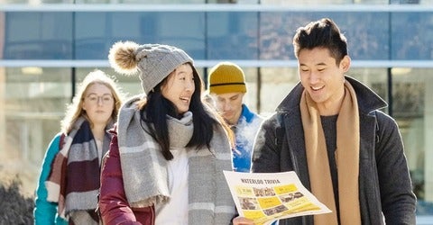 Students walk holding an open house flyer