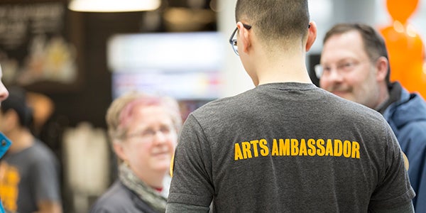 An Arts Ambassador talks to a family at an event