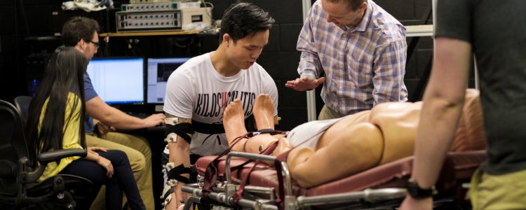 Students working lifting a manequin with the help of biomechanics devices 
