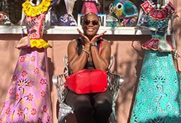 Akua sits and smiles beside colourful dresses