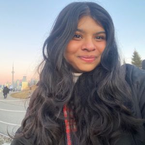 Amrita smiles outside with the CN Tower in the background