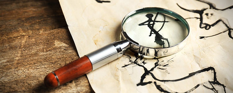 A magnifying glass rests on paper with simple ink drawings